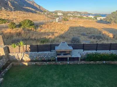 a backyard with a stone wall and a grill at Villa Poseidon Blue in Rhodes Town