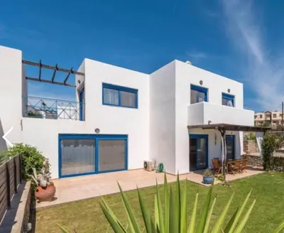 a white house with blue windows and a yard at Villa Poseidon Blue in Rhodes Town