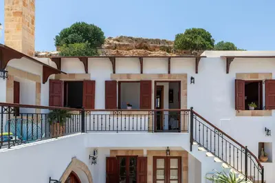 a white building with balconies and doors at Lindos Luxury Belfry Apartment in Líndos