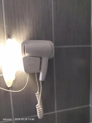 a white phone in a bathroom with a light at Periklis House in Ixia