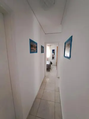 a hallway with white walls and paintings on the walls at Periklis House in Ixia