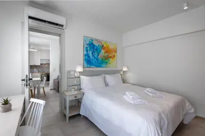 a white bedroom with a white bed and a table at cattleya suite lindos in Líndos