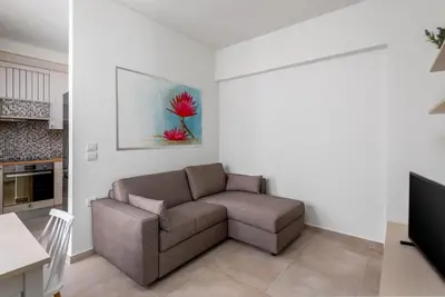 a living room with a couch and a television at cattleya suite lindos in Líndos