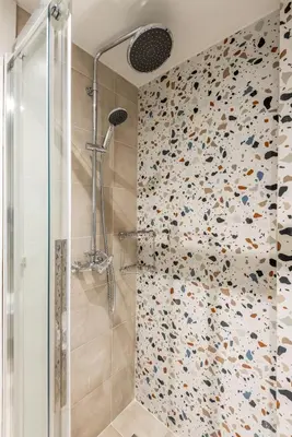a bathroom with a shower with a tiled wall at cattleya suite lindos in Líndos