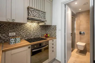 a kitchen with white cabinets and a stove top oven at cattleya suite lindos in Líndos
