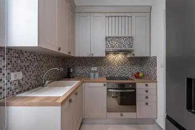 a kitchen with white cabinets and a sink at cattleya suite lindos in Líndos