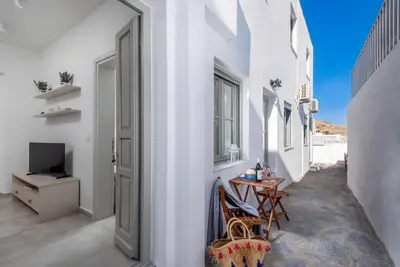a hallway with white walls and a table and chairs at cattleya suite lindos in Líndos