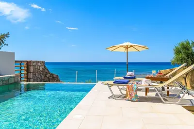 a swimming pool with an umbrella and a table and a chair and an umbrella at Anima Maris in Kiotari