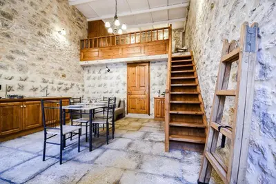 a kitchen with a table and chairs and a staircase at Stone Living Symi Central Apartments in Symi