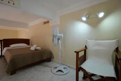 a bedroom with a bed and a fan and a chair at Stone Living Symi Central Apartments in Symi