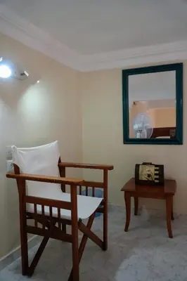 a room with a chair and a table and a mirror at Stone Living Symi Central Apartments in Symi