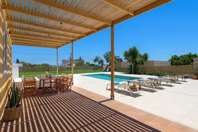 a patio with a table and chairs and a pool at Villa Dorinna in Lachania