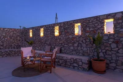a patio with a stone wall with a table and chairs at Villa Dorinna in Lachania