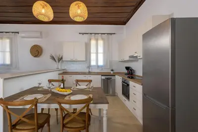 a kitchen with a table with chairs and a refrigerator at Villa Dorinna in Lachania