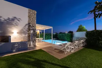 a patio with chairs and a swimming pool at night at New Loft by Ossiano Pool Villas, Heating Pool,2 min drive to Haraki Beach & 10 to Lindos in Haraki