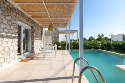 a patio with a table and chairs next to a swimming pool at New Loft by Ossiano Pool Villas, Heating Pool,2 min drive to Haraki Beach & 10 to Lindos in Haraki