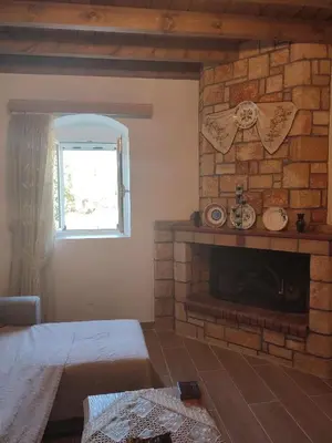 a living room with a brick fireplace and a window at Villa Jimmy, Pilona Village in vlicha