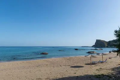 a beach with chairs and an umbrella and the ocean at Stegna Holiday in Archangelos