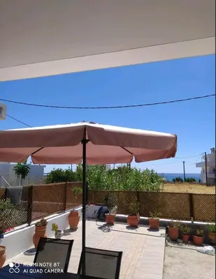a large umbrella sitting on a patio with plants at Stegna Holiday in Archangelos
