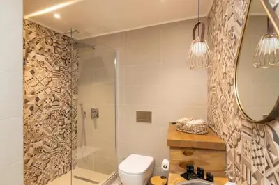 a bathroom with a shower and a toilet and a mirror at Kyrangelo Traditional House with outdoor jacuzzi in Koskinou