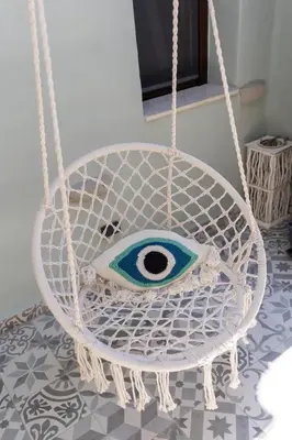 a white swing with an eye on it at Kyrangelo Traditional House with outdoor jacuzzi in Koskinou