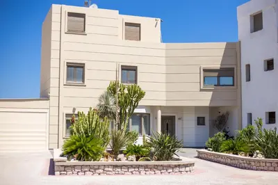 a large building with palm trees in front of it at Des & Coo Luxury Villa with Private Pool in Faliraki