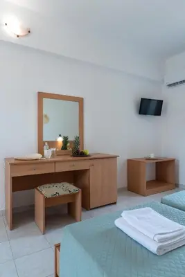 a bedroom with two beds and a vanity with a mirror at Yiasemi Faliraki Rooms in Faliraki