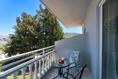 a balcony with a table and chairs and a window at Yiasemi Faliraki Rooms in Faliraki