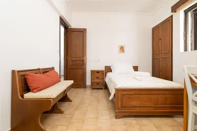 a bedroom with two beds and a bench and a window at House of Flowers in Rhodes Town