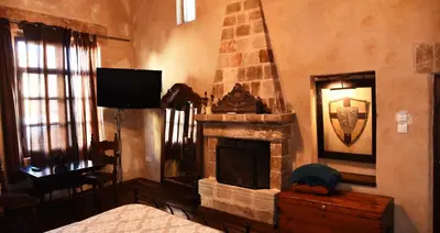 a bedroom with a fireplace and a bed and a television at The Dragon of Rodos in Rhodes Town