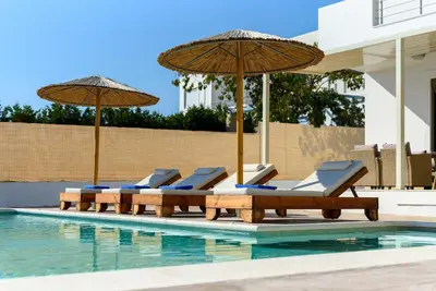 a group of chairs and umbrellas next to a swimming pool at Acro Villa in Afantou
