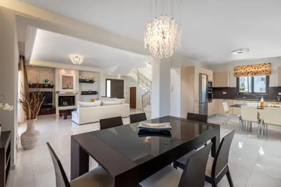 a dining room and living room with a table and chairs at Acro Villa in Afantou