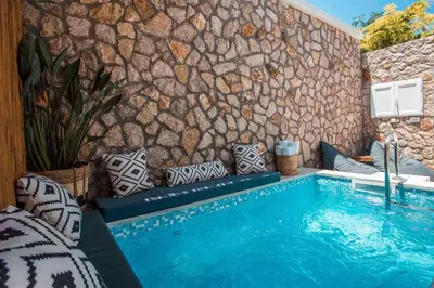 a swimming pool with pillows next to a stone wall at Demar luxury villa in Rhodes Town