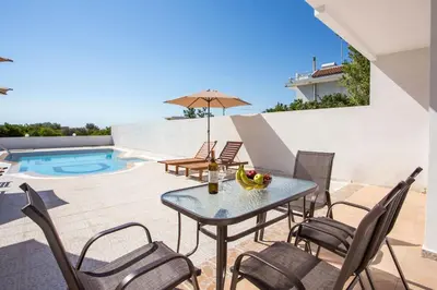 a patio with a table and chairs and a pool at Anastasia Private Pool Apartment in Afantou