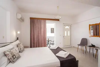 a bedroom with a large white bed and a table at Anastasia Apartment in Afantou