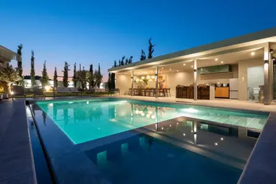 a swimming pool in front of a house at night at Villa Nikoli in Kolimbia