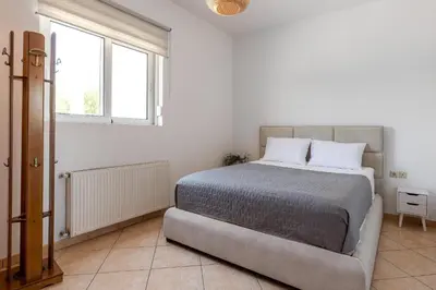 a bedroom with a large bed in a white room at Villa Nikoli in Kolimbia