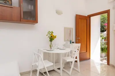 a white dining room with a white table and chairs at Ibiscus and Lily Apartments in Rhodes Town