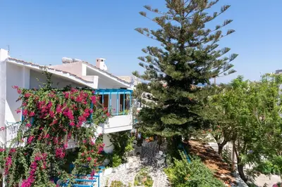 a house with flowers on the balconies and a pine tree at Ibiscus and Lily Apartments in Rhodes Town