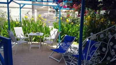 a patio with a table and chairs and flowers at Ibiscus and Lily Apartments in Rhodes Town