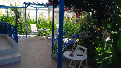 a patio with tables and chairs in a garden at Ibiscus and Lily Apartments in Rhodes Town