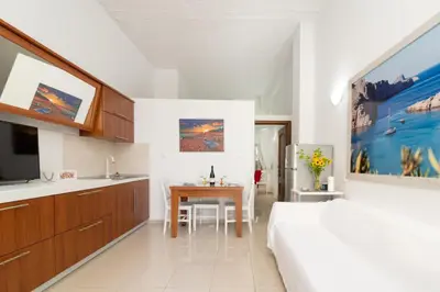 a bedroom with a bed and a table and a kitchen at Ibiscus and Lily Apartments in Rhodes Town