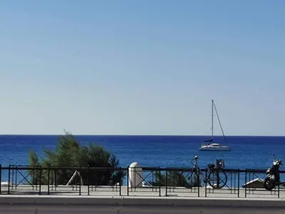 a bike parked next to the ocean with a sail boat at Blue View Zefiros in Rhodes Town