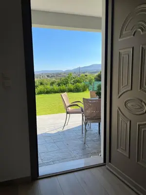 a door leading to a patio with a table and chairs at Elena villa-apartments in Asklipiḯon