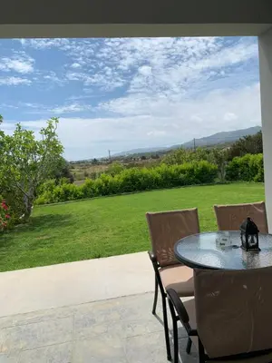 a table and chairs with a view of a field at Elena villa-apartments in Asklipiḯon
