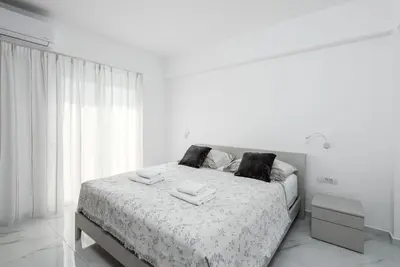 a white bedroom with a bed with towels on it at Viviane Paulos Villa in Gennadi