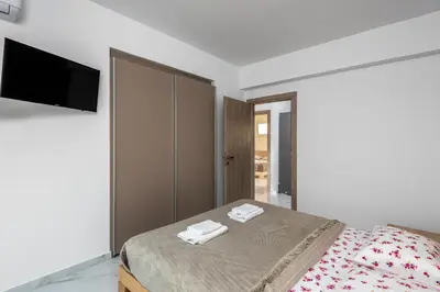 a bedroom with a bed and a flat screen tv at Viviane Paulos Villa in Gennadi