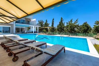 a swimming pool with lounge chairs and a house at Viviane Paulos Villa in Gennadi