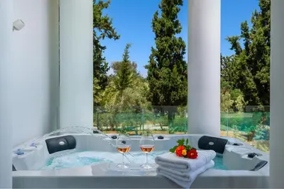 a bathroom with a tub with two glasses of wine at Viviane Paulos Villa in Gennadi