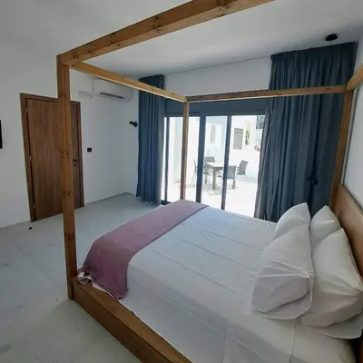 a bedroom with a wooden canopy bed with a window at Courtyard Luxury Suites “ APOSTOLOS” in Pefki Rhodes